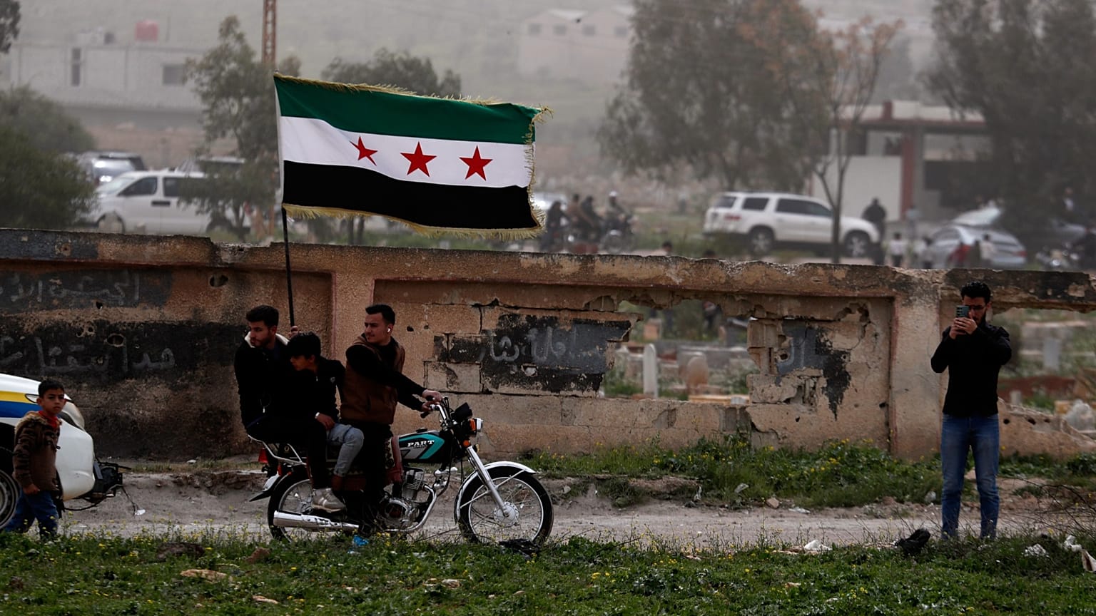 متظاهرون يرفعون العلم السوري خلال تجمع في درعا لإحياء الذكرى الـ15 للانتفاضة ضد نظام بشار الأسد، 18 مارس/آذار 2026.