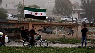 متظاهرون يرفعون العلم السوري خلال تجمع في درعا لإحياء الذكرى الـ15 للانتفاضة ضد نظام بشار الأسد، 18 مارس/آذار 2026.