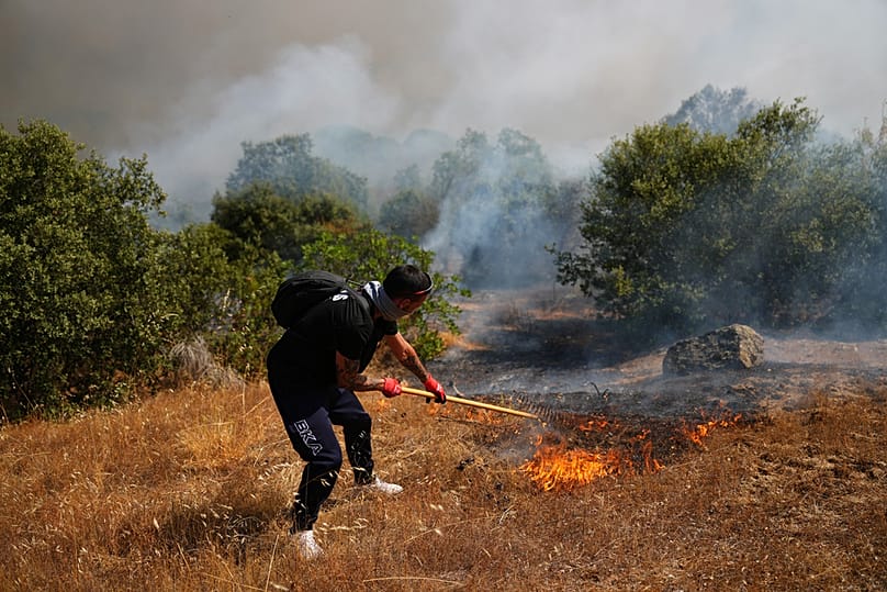 A volunteer uses a rake trying to help stop a wildfire from advancing in San Martin de Valdeiglesias, west of Madrid, Spain, Sunday, July 26, 2026