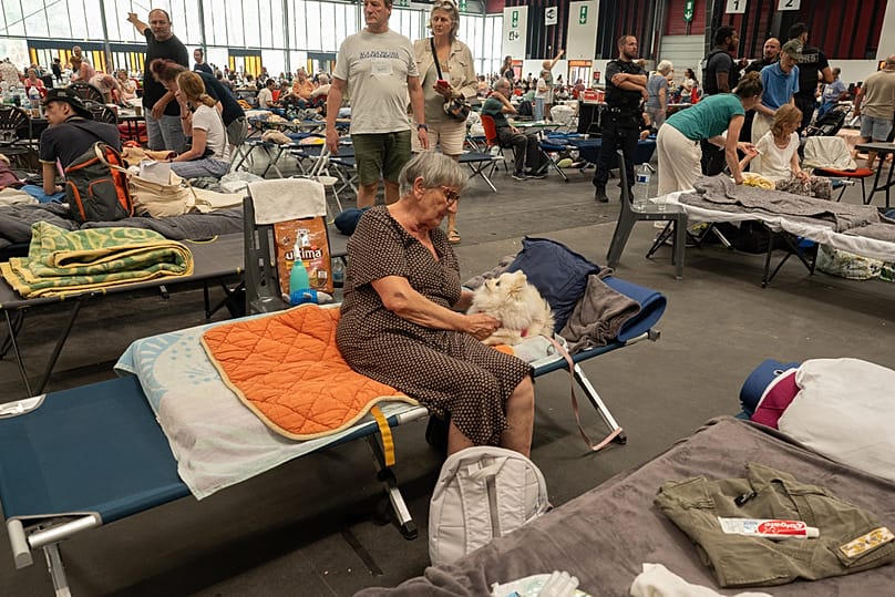 A woman caresses her dog at a shelter set up in the Bordeaux Exhibition Centre for those evacuated amid the raging wildfires, Bordeaux, France, Sunday, July 26, 2026