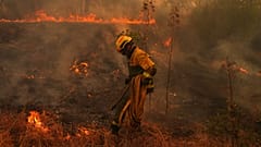 Un vigile del fuoco trasporta una manichetta mentre combatte un incendio boschivo a San Martín de Valdeiglesias, a ovest di Madrid, Spagna, il 26 luglio 2026.