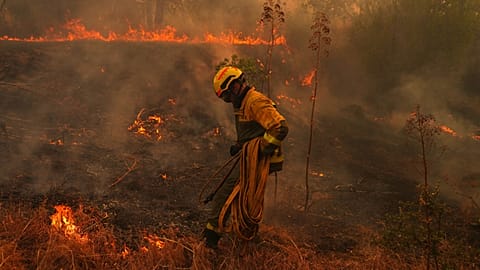 A firefighter carries a hose while battling a wildfire in San Martin de Valdeiglesias, west of Madrid, Spain, Sunday, July 26, 2026.
