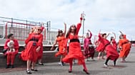 Vörösbe öltözött Kate Bush-rajongók százai melegítenek be, mielőtt újraalkotják a „Wuthering Heights” klipet Folkestone-ban, Angliában 2026. július 26-án, vasárnap.