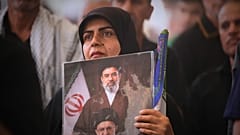 Una mujer lleva una imagen de Mojtaba Jamenei, nuevo líder supremo, y de su padre fallecido durante el funeral en el santuario del imán Ali.