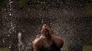 Una donna si rinfresca in una fontana in un parco lungo il fiume a Madrid, in Spagna, mercoledì 15 giugno 2022.