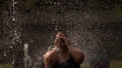 Una donna si rinfresca in una fontana in un parco lungo il fiume a Madrid, in Spagna, mercoledì 15 giugno 2022.