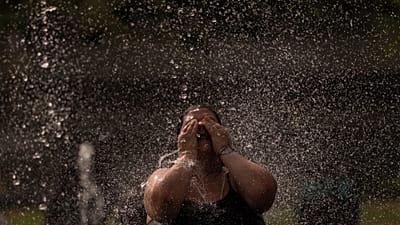 A woman cools off in a fountain in a park by the river in Madrid, Spain, Wednesday, June 15, 2022. 