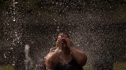 A woman cools off in a fountain in a park by the river in Madrid, Spain, Wednesday, June 15, 2022. 