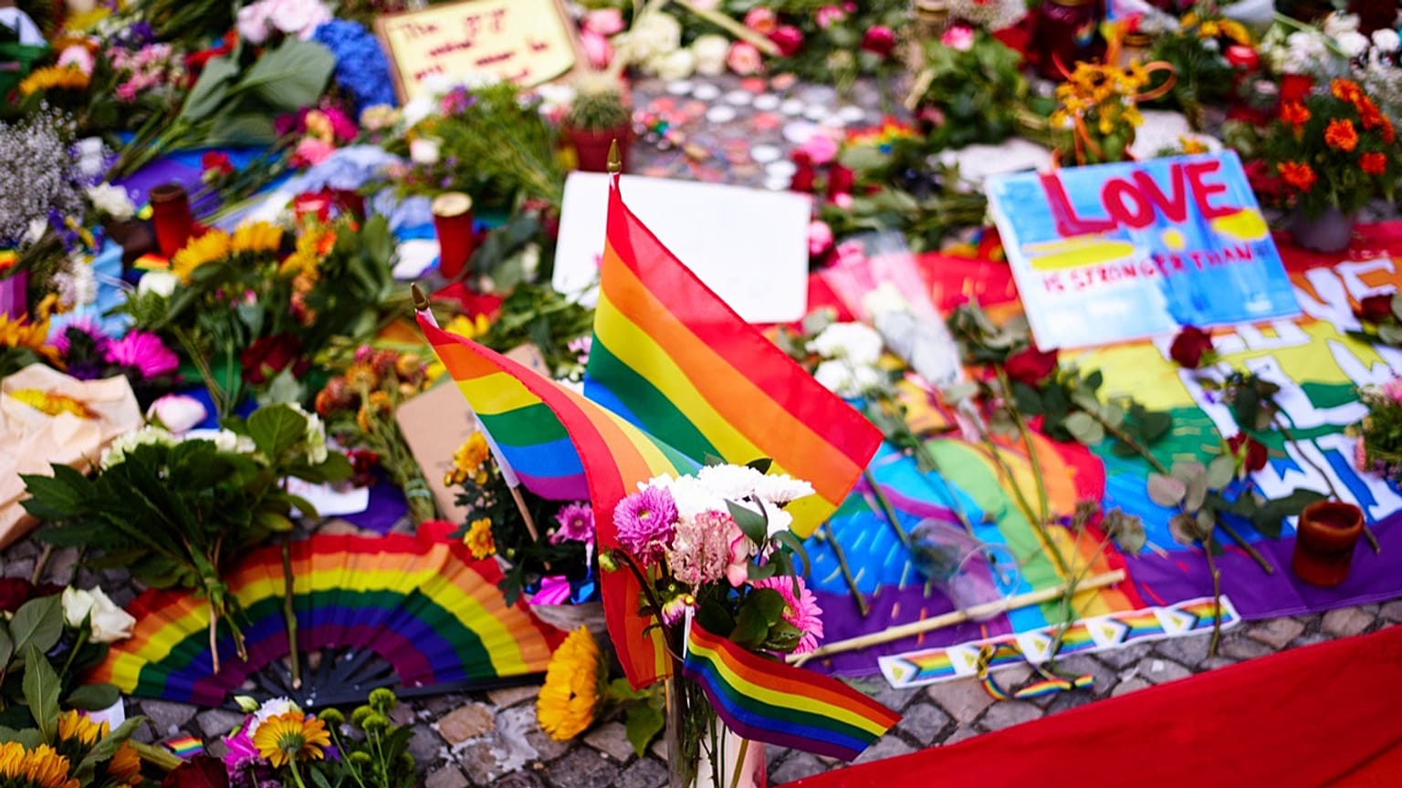 Flowers and rainbow flags placed in front of the Brandenburg Gate commemorating the victims of a car attack on Saturday's Pride March in Berlin, Germany, Monday, July 27, 2026