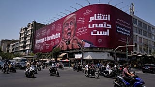 راكبو دراجات نارية يمرون أمام لوحة إعلانية في طهران تصور ترامب واضعاً يديه حول رقبته مع رسالة "الانتقام أمر لا مفر منه" بالإنجليزية والفارسية، الاثنين 27 يوليو.