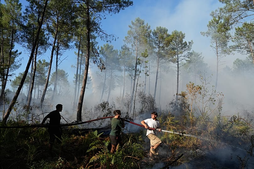 Des hommes tiennent une lance à incendie et tente d'éteindre un feu près de Lacanau, alors que des feux de forêt font rage aux alentours de Bordeaux