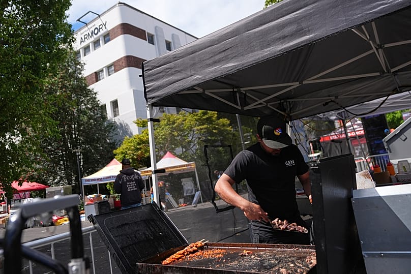 A vendor throws away food while cleaning up the day after a shooting at Seattle Center during the Bite of Seattle food festival, Monday, July 27, 2026, in Seattle