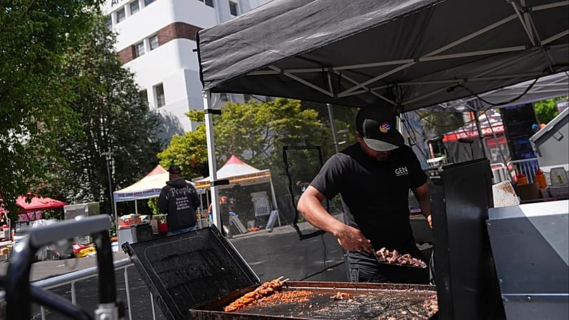 Ein Standbetreiber entsorgt Lebensmittel bei den Aufräumarbeiten einen Tag nach der Schießerei im Seattle Center während des Food-Festivals „Bite of Seattle“ am Montag, 27. Juli 2026, in Seattle.