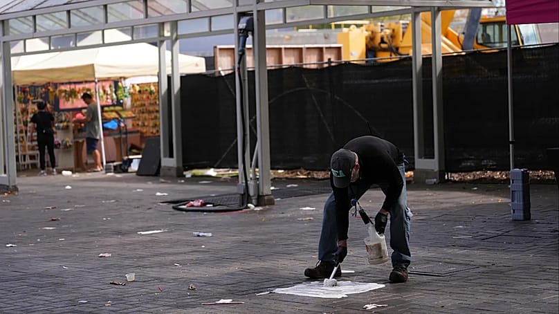 Ein Arbeiter reinigt Blut von der Straße, einen Tag nach der Schießerei im Seattle Center während des Food-Festivals „Bite of Seattle“ am Montag, 27. Juli 2026.