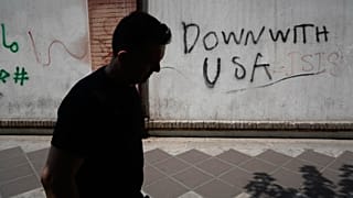 رجل يمر أمام كتابات مناهضة للولايات المتحدة على جدار السفارة البريطانية في طهران، إيران، الاثنين 27 تموز/يوليو 2026.