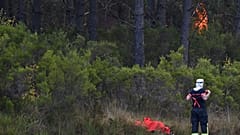 Un bombero ajusta su traje mientras un incendio arrasa un bosque cerca de Saint-Jean-d'Illac, en el suroeste de Francia, el martes 28 de julio de 2026.