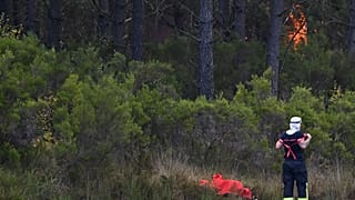 Strażak poprawia mundur, gdy w lesie niedaleko Saint-Jean-d'Illac płonie ogień, podczas pożarów lasów w południowo-zachodniej Francji, wtorek, 28 lipca 2026 r.