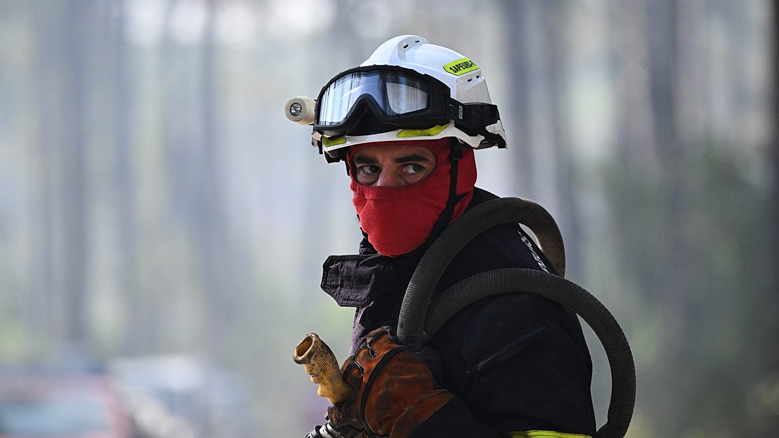 A firefighter carries his equipment as he works to suppress a fire in a forest in Claouey, during wildfires in the area of southwestern France, Tuesday, July 28, 2026. 