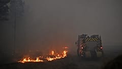 Un camión de bomberos atraviesa el humo de un incendio forestal que asola la zona de Marcheprime, en las afueras de Burdeos, Francia, el 26 de julio de 2026.