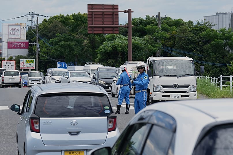 Police officers control the traffic near AEON Mall, which was destroyed by an explosion following an earthquake, in Kashima, Kumamoto, southern Japan, Wednesday, July 29, 2026