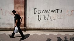 Un hombre pasa junto a pintadas contra Estados Unidos en el muro de la Embajada británica en Teherán, Irán, lunes 27 de julio de 2026