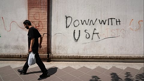 A man walks past anti-US graffiti on the wall of the British Embassy in Tehran, Iran, Monday, July 27, 2026