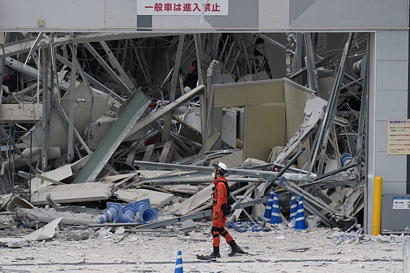 A rescue worker walks in front of AEON Mall, which was damaged by an explosion following an earthquake, is seen in Kashima, 29 July, 2026