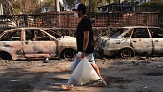 A man carries his belongings as a wildfire continues to spread near Navas del Rey, Ávila province, Spain, Tuesday, July 28, 2026.