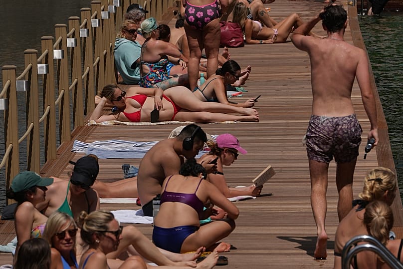Pessoas sentadas numa piscina pública ao ar livre em Londres, numa altura em que se prevê o desenvolvimento de uma onda de calor nos próximos dias, sexta-feira, 19 de junho de 2026. (Foto AP/Kin Cheung)