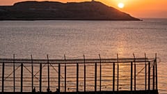 Marokkói férfiak halásznak a spanyol határ marokkói oldalán, ahogy az a spanyol Ceuta enklávé Benzu negyedéből látható, 2021. június 3-án.