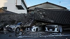 Veículos esmagados sob edifícios colapsados em Yatsushiro, no sudoeste do Japão, quarta-feira, 29 de julho de 2026, um dia após um terramoto atingir a área