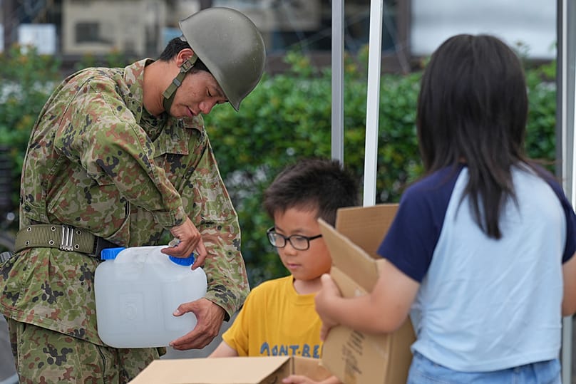 A Self-Defence Force member helps provide water to residents affected by an earthquake at Hikawa Town Hall, Kumamoto Prefecture, southern Japan, Thursday, July 30, 2026
