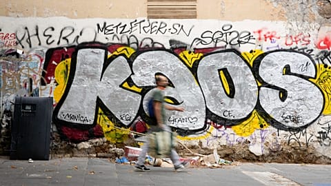 FILE: A man walks past graffiti in a dirty street of Rome's St. Lorenzo's neighbourhood, Friday, Sept. 17, 2021.