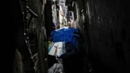 ARQUIVO - Uma mulher caminha por um beco, protegendo-se com um guarda-chuva com a imagem da estátua do Cristo Redentor, na favela da Rocinha,