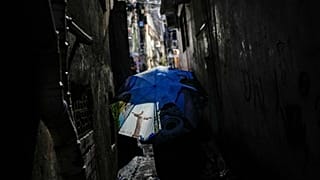 ARQUIVO - Uma mulher caminha por um beco, protegendo-se com um guarda-chuva com a imagem da estátua do Cristo Redentor, na favela da Rocinha,