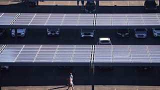 Des personnes traversent un parking doté de panneaux solaires près du Lincoln Financial Field, le 8 septembre 2025, à Philadelphie.