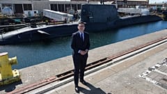 Primeiro-ministro britânico Andy Burnham posa frente ao HMS Agamemnon em visita à Submarine Academy for Skills and Knowledge da BAE Systems, Inglaterra, 30 jul. 2026