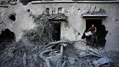 رجل فلسطيني يزيل الأنقاض من مبنى دمر في غارة جوية إسرائيلية في دير البلح بوسط قطاع غزة، الأربعاء 29 يوليو 2026. (AP Photo/عبد الكريم حنا)