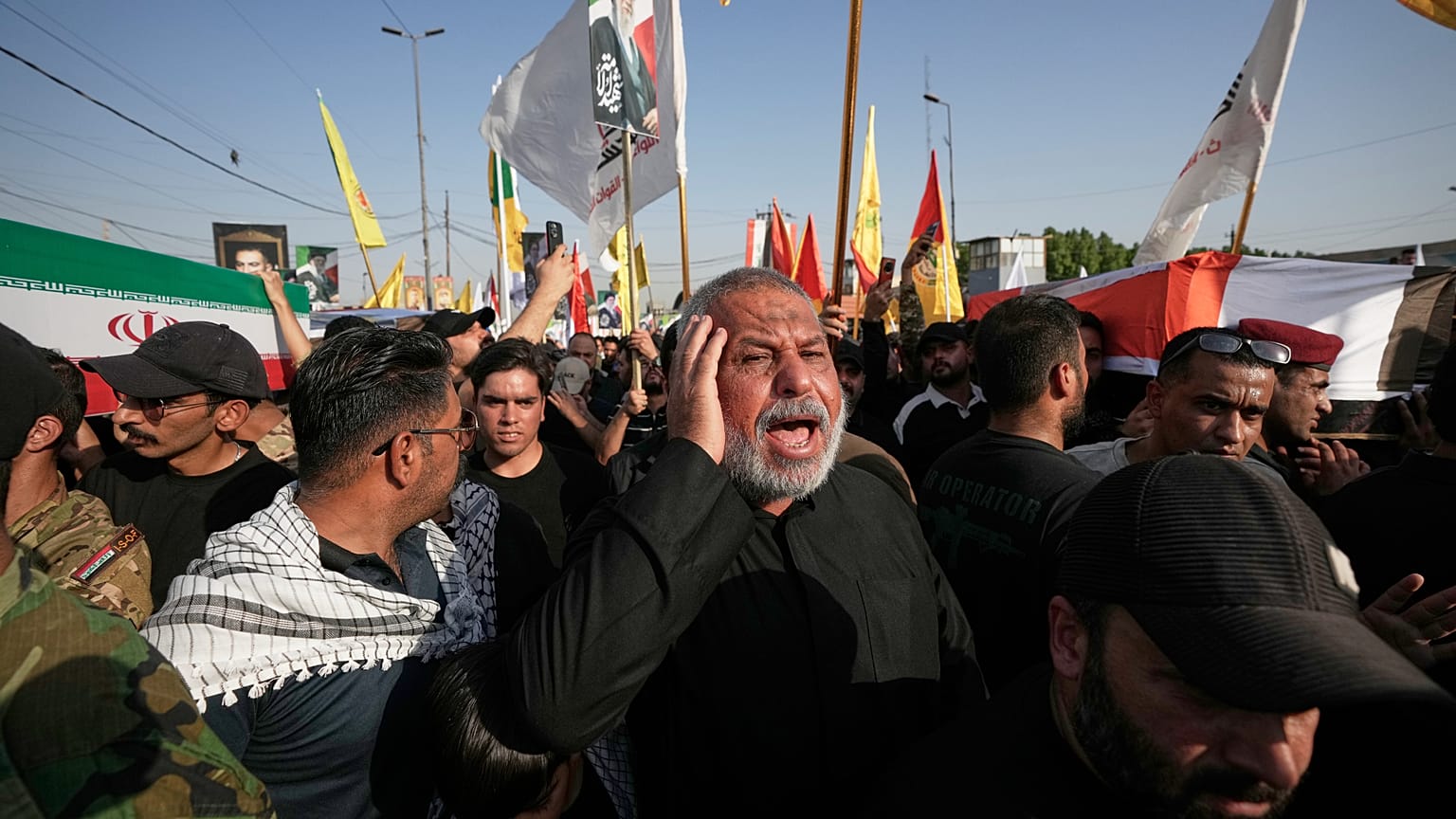 يحمل المشيعون توابيت ملفوفة بالعلم الإيراني على اليسار والعلم العراقي على اليمين خلال جنازة جماعية للمستشارين الإيرانيين ومقاتلي قوات التعبئة الشعبية الذين قتلوا في غارات جوية