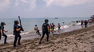 Agentes da polícia espanhola intervêm enquanto migrantes atravessam a fronteira de Marrocos para o enclave espanhol de Ceuta