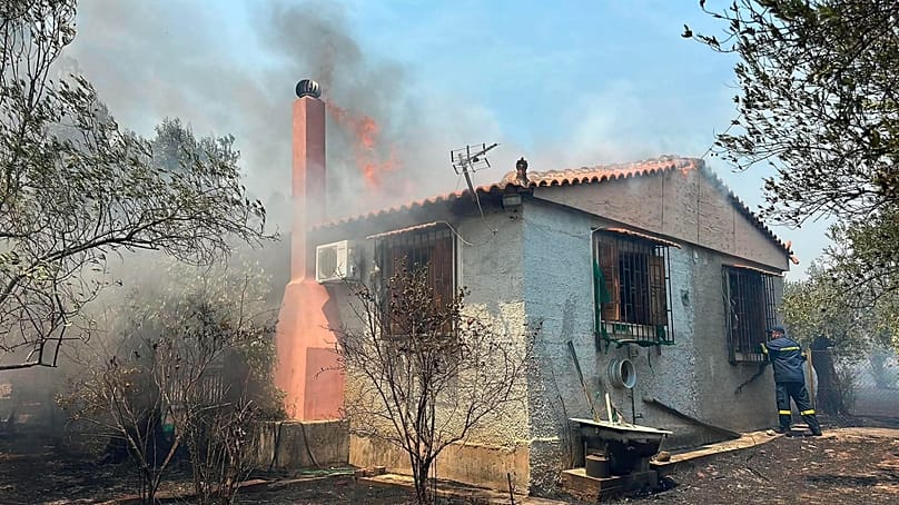 Πυροσβέστες προσπαθούν να σβήσουν φωτιά σε κατοικία, κατά τη διάρκεια μεγάλης φωτιάς που καίει στην περιοχή Φίχτια Αργολίδας