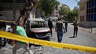 أفراد الأمن السوريون يتفقدون سيارة محترقة بالقرب من فندق فور سيزونز 