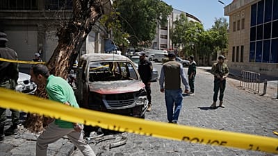 أفراد الأمن السوريون يتفقدون سيارة محترقة بالقرب من فندق فور سيزونز 