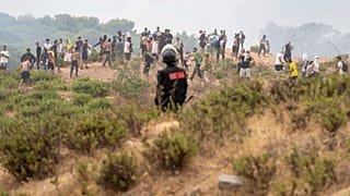 Eine marokkanische Sicherheitskraft sichert die Grenze, während Menschen versuchen, von der nordmarokkanischen Stadt Fnideq in die spanische Exklave Ceuta zu gelangen.