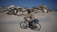 رجل فلسطيني يركب دراجته وسط أنقاض المباني التي دمرت خلال حرب حماس الإسرائيلية، في خان يونس، جنوب قطاع غزة، الجمعة 31 يوليو 2026.