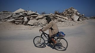 رجل فلسطيني يركب دراجته وسط أنقاض المباني التي دمرت خلال حرب حماس الإسرائيلية، في خان يونس، جنوب قطاع غزة، الجمعة 31 يوليو 2026.