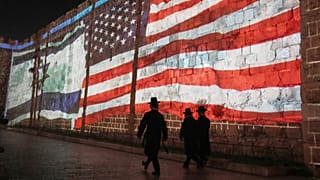 صورة لعلمَي الولايات المتحدة وإسرائيل على أسوار البلدة القديمة في القدس، الأحد 22 يوليو/تموز 2025