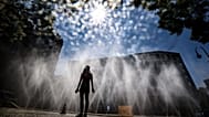 Eine Frau steht in Köln vor Schläuchen, aus denen ein feiner Wassernebel gesprüht wird, Deutschland, Mittwoch, 29. Juli 2026.