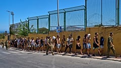 Migrantes que entraram em Ceuta são escoltados por soldados espanhóis até à fronteira hispano-marroquina, para regressarem a Marrocos, domingo, 2 ago. 2026
