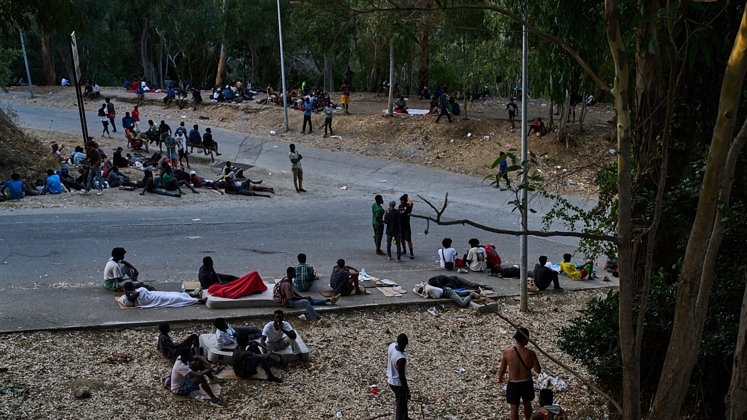 Migrants who crossed into Spain from Morocco sit outside the temporary immigrant stay center (CETI) in the Spanish enclave of Ceuta, Sunday, Aug. 2, 2026.